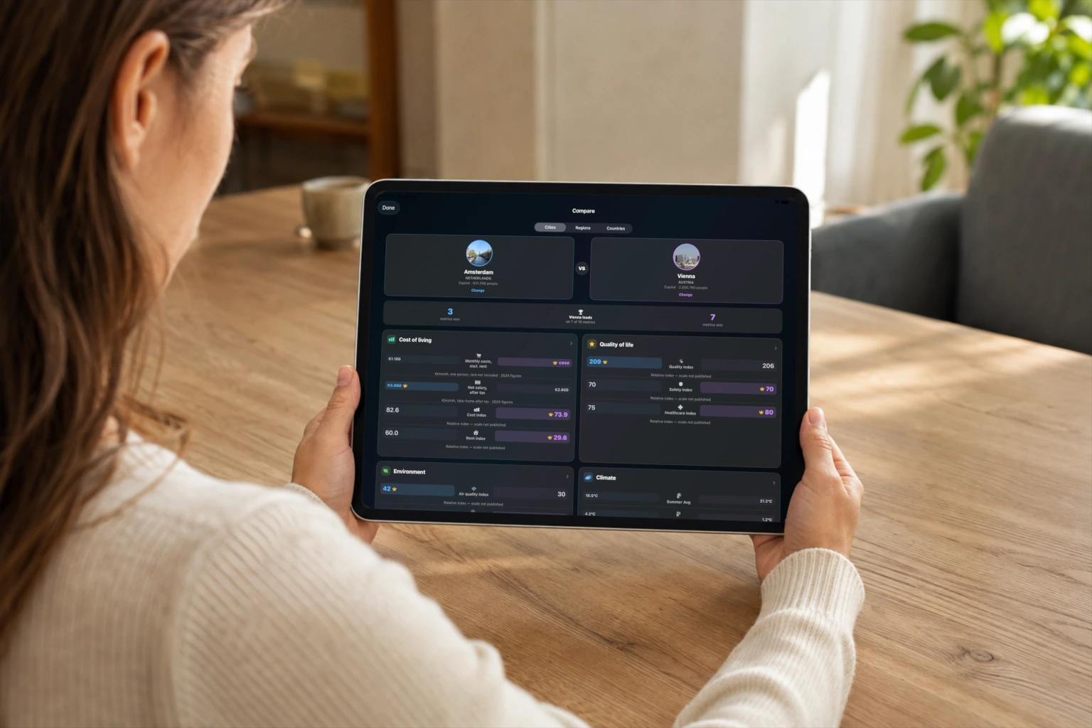 A person holds an iPad showing the mEUvy Amsterdam and Vienna comparison